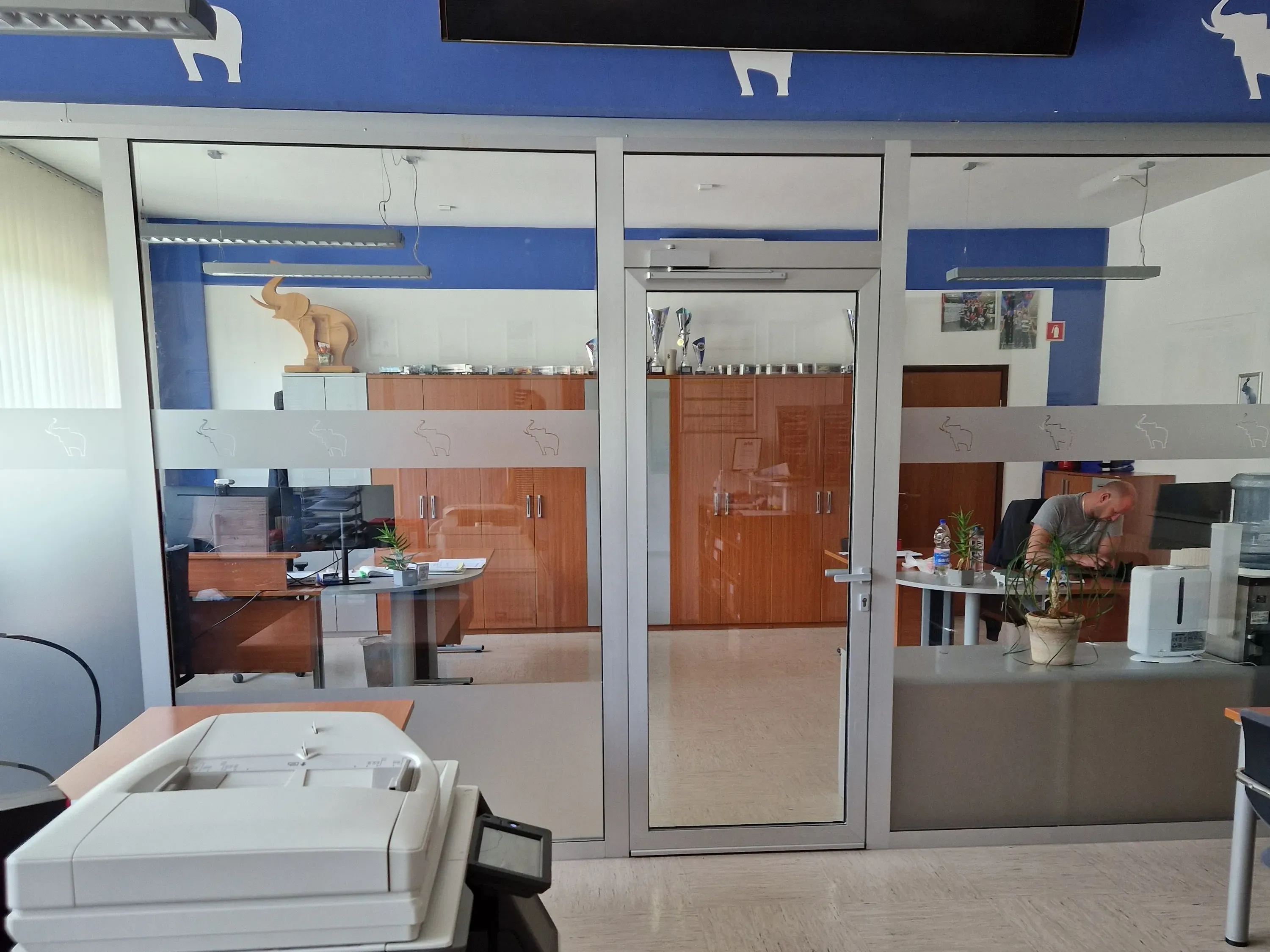 A cozy office at Schmitz Cargobull AG featuring a person working at a desk, with blue and white decor and elephant motifs.