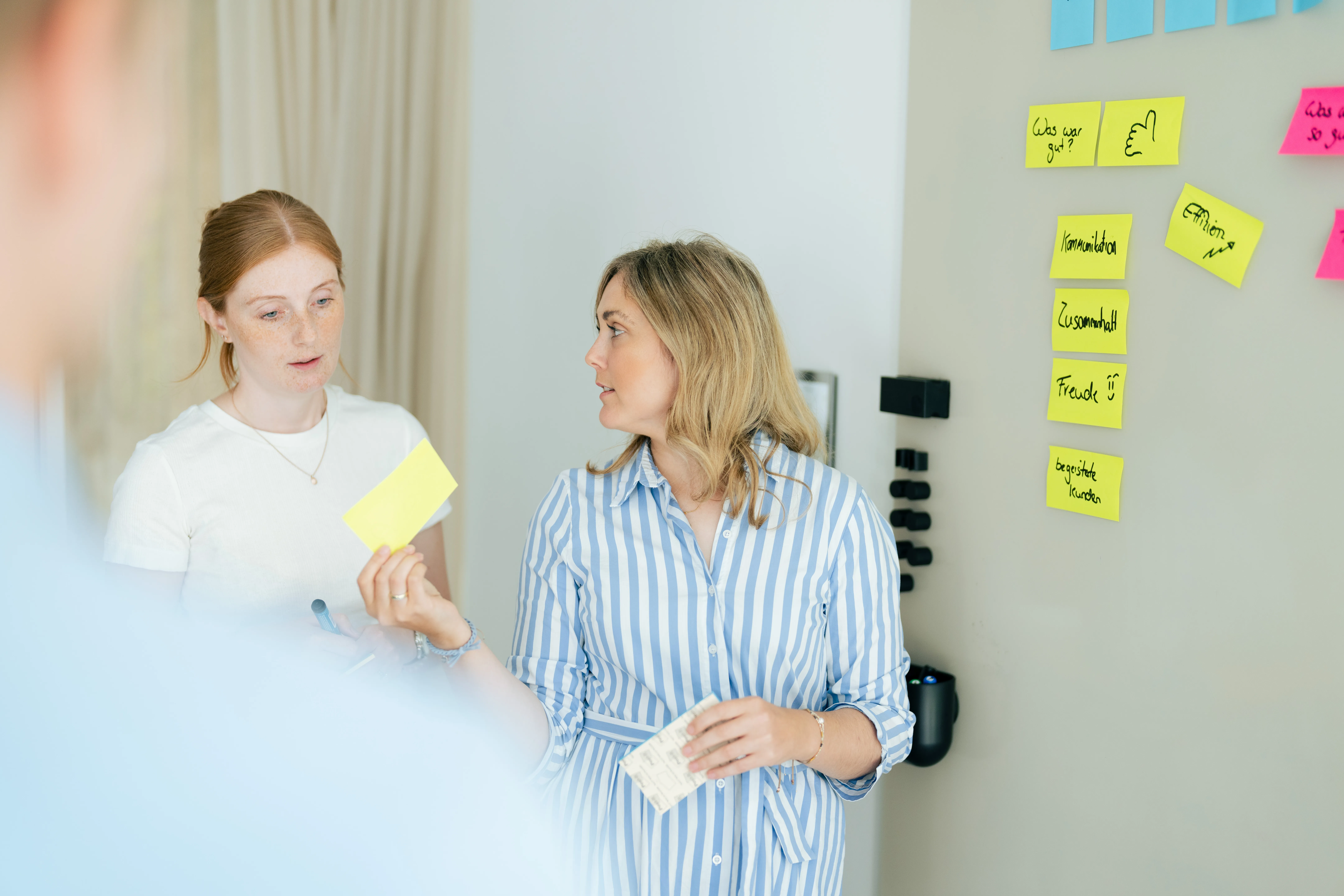 Vier junge Frauen sitzen auf Treppenstufen und arbeiten gemeinsam an Laptops und Notizbüchern.
