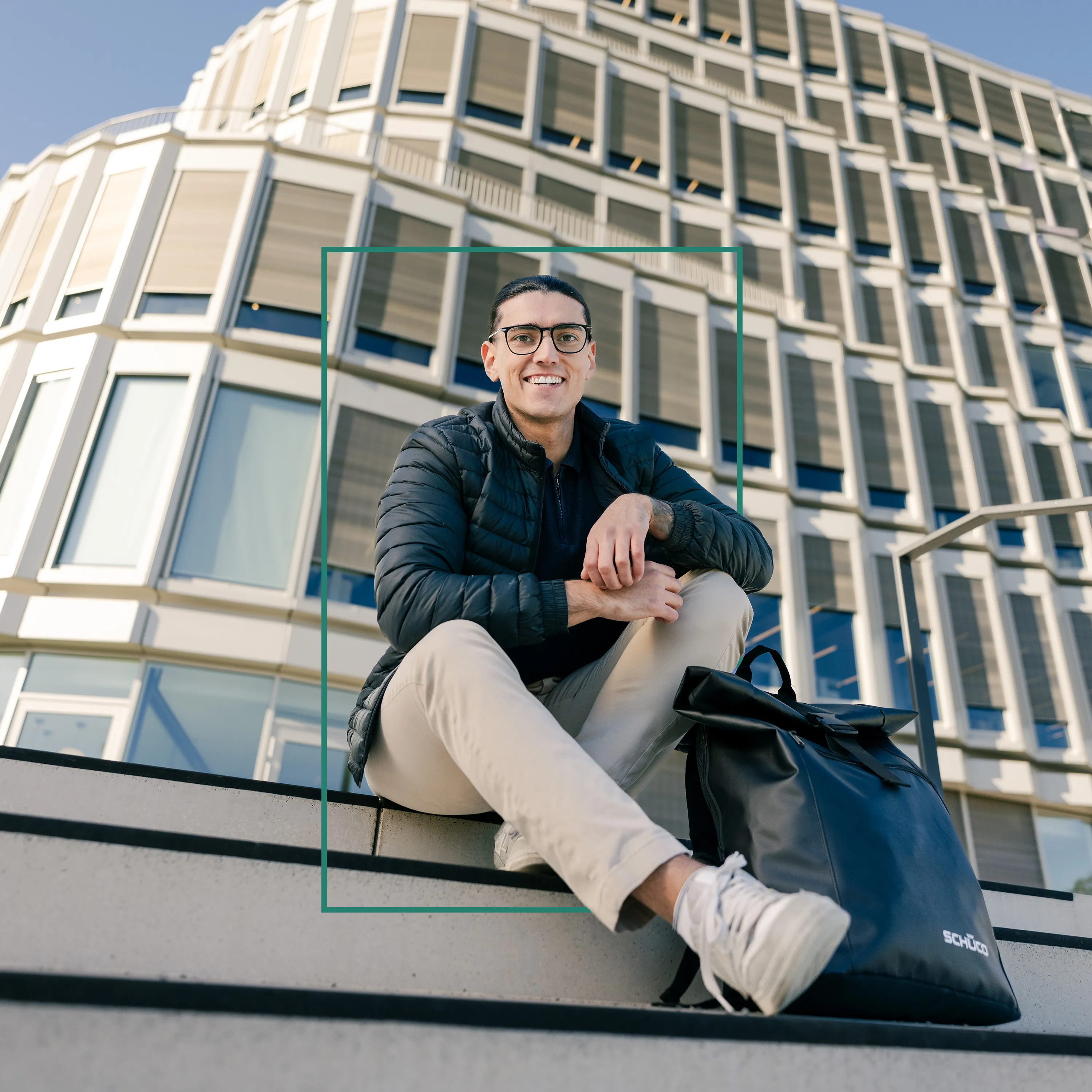 Eine junge Frau telefoniert lachend in einer modernen Bürokabine mit grünen Wänden und großen Fenster. Auch Studierende können bei Schüco einsteigen.