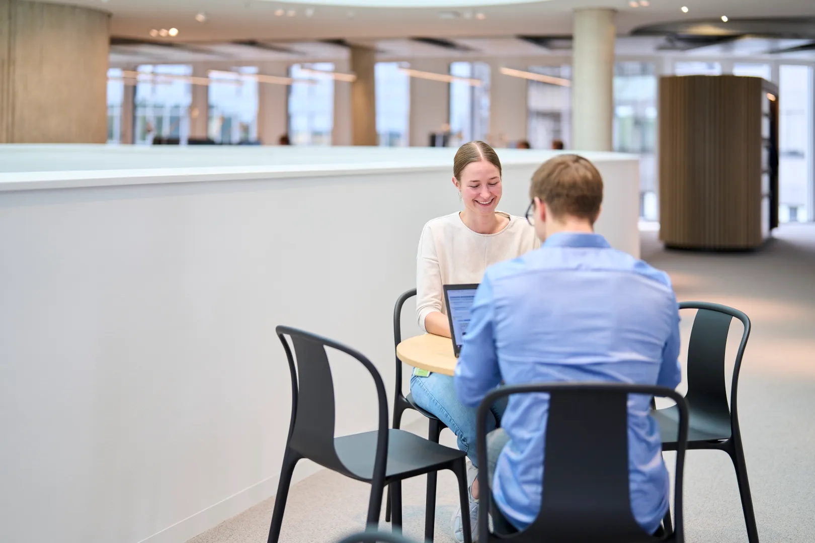 Mehrere Hände von Mitarbeitern treffen sich in der Mitte eines Tisches mit Laptops und Dokumenten zu einem Fistbump, symbolisieren Teamarbeit.