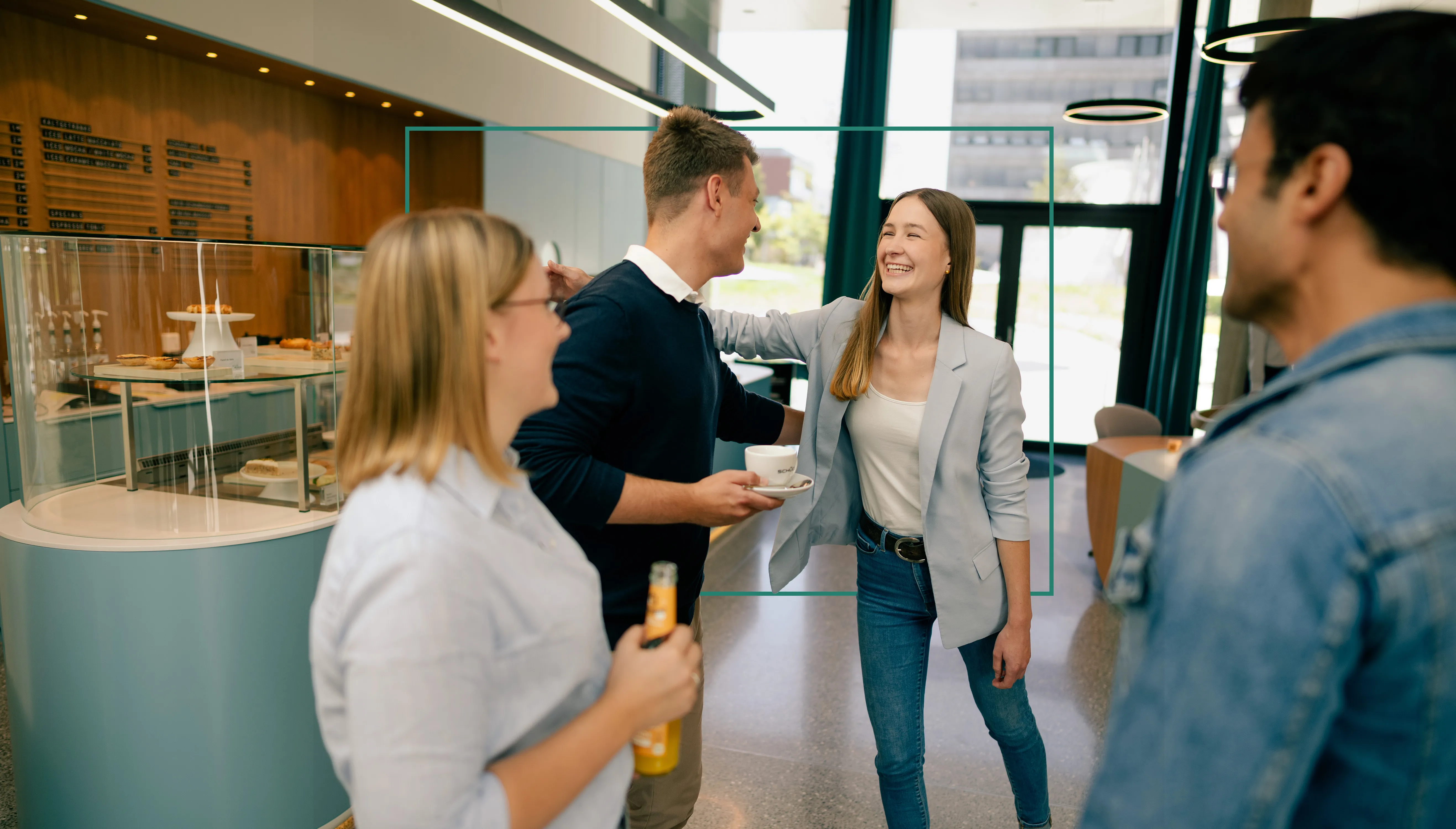 Eine Gruppe junger Auszubildender in einem modernen Café-Bereich bei Schüco, die miteinander lachen und sich unterhalten.