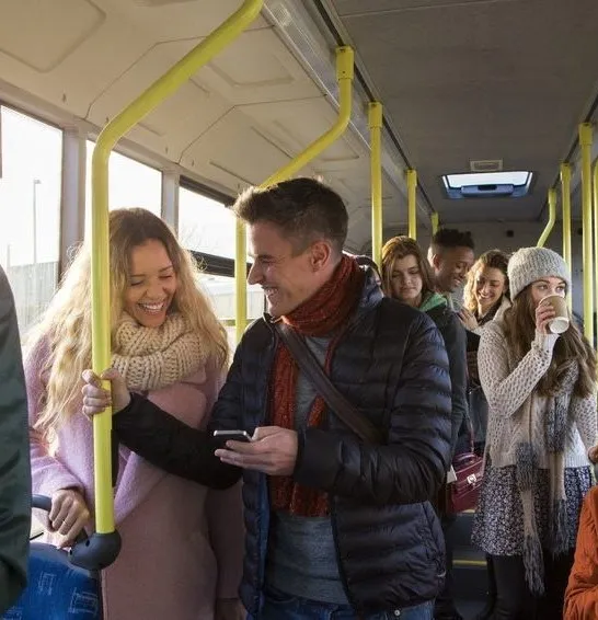 Personen in einem Bus, die lächeln und miteinander sprechen. Geeignet für eine Karrierewebsite im Gesundheitswesen.