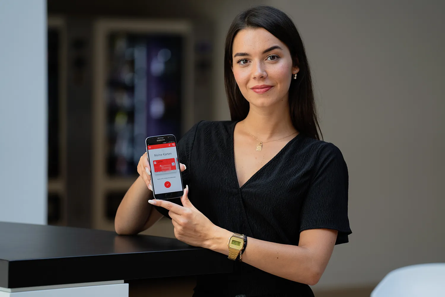 Eine Frau zeigt die Sparkasse-App auf ihrem Smartphone, die den Bereich "Meine Karten" anzeigt.