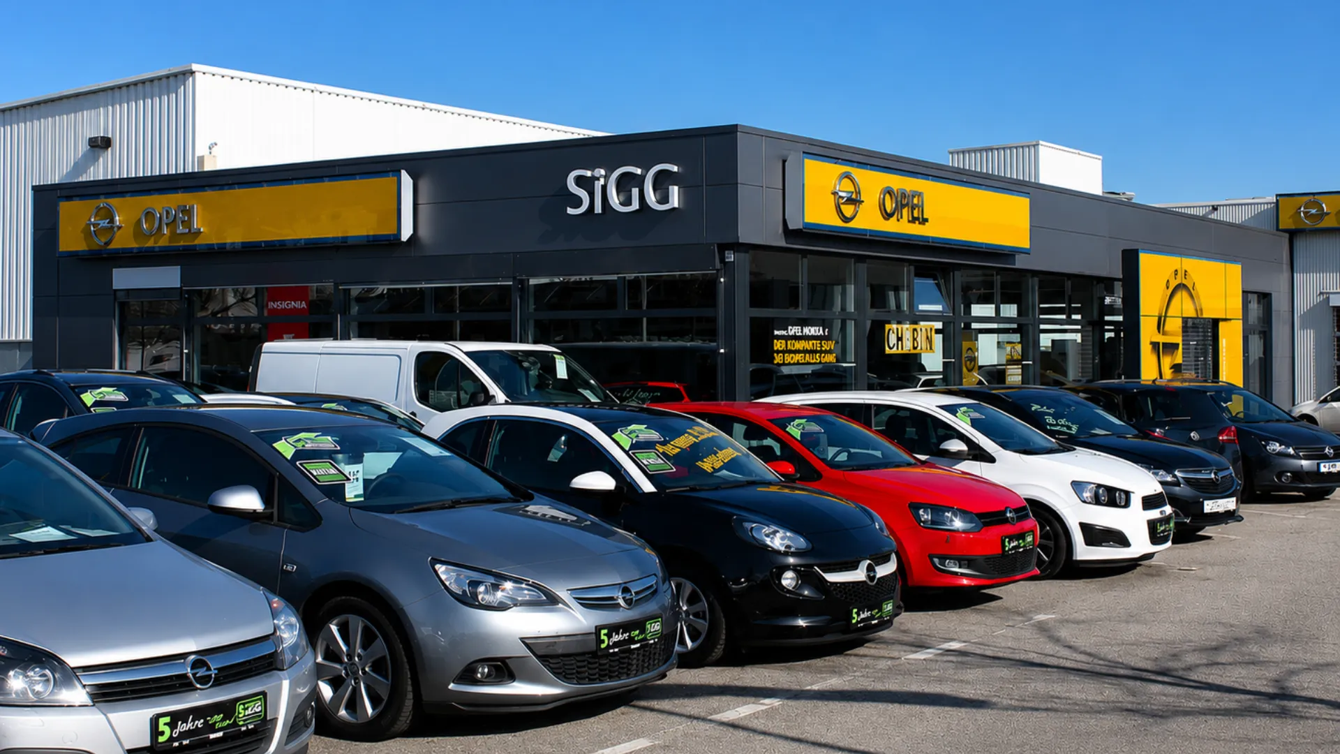 Mehrere Opel-Fahrzeuge stehen vor einem modernen Autohaus, bereit für Dich als Teil des Stellantis-Teams.