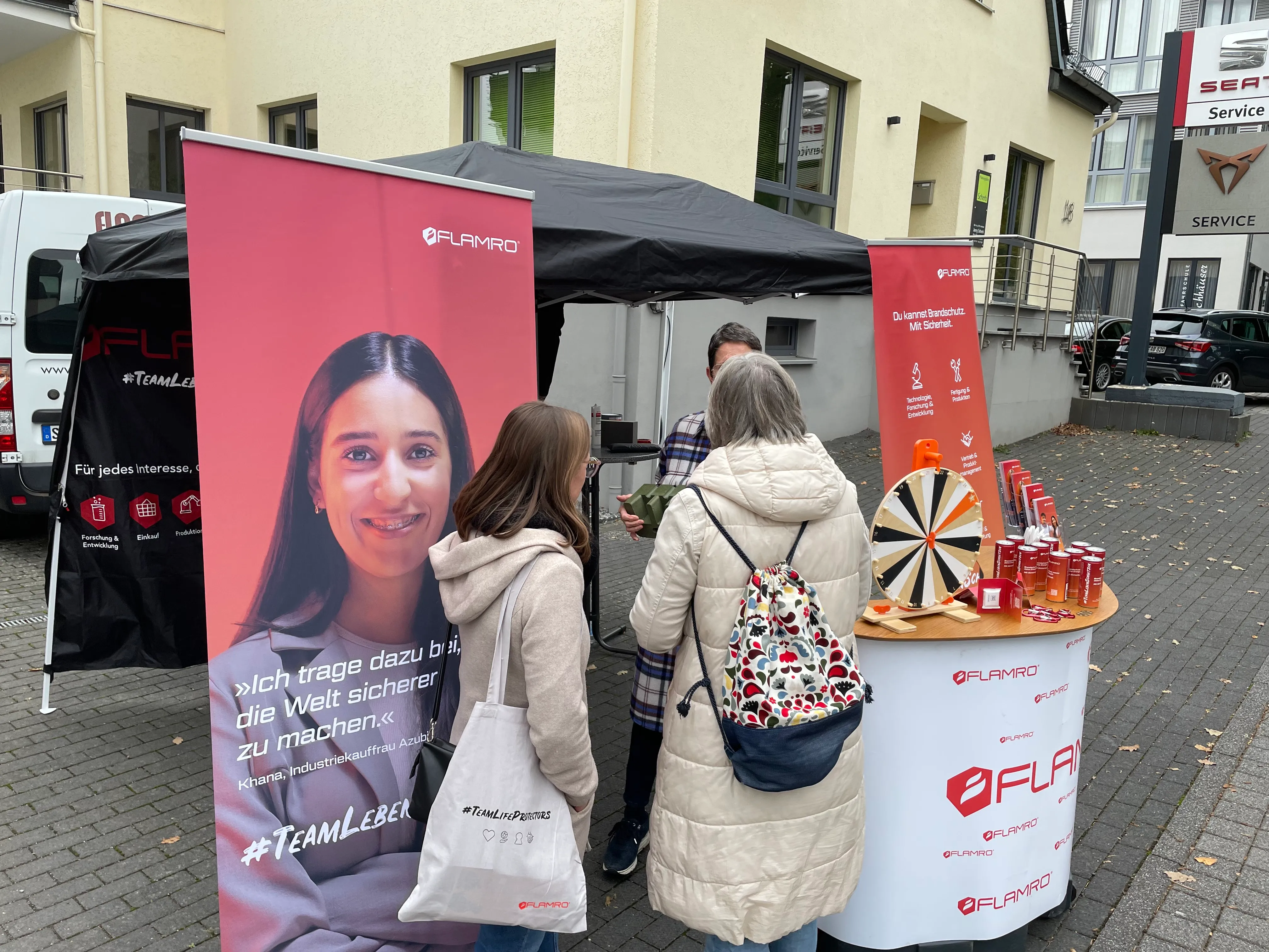 Ein Mitarbeiter von svt Holding GmbH spricht mit einem Interessenten an einem Messestand mit FLAMRO-Branding.