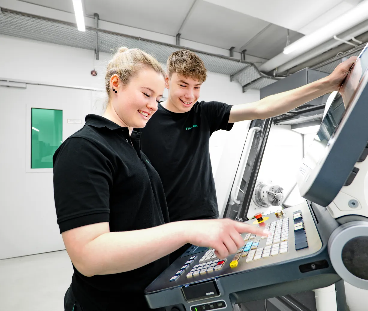 2 smiling interns at machine