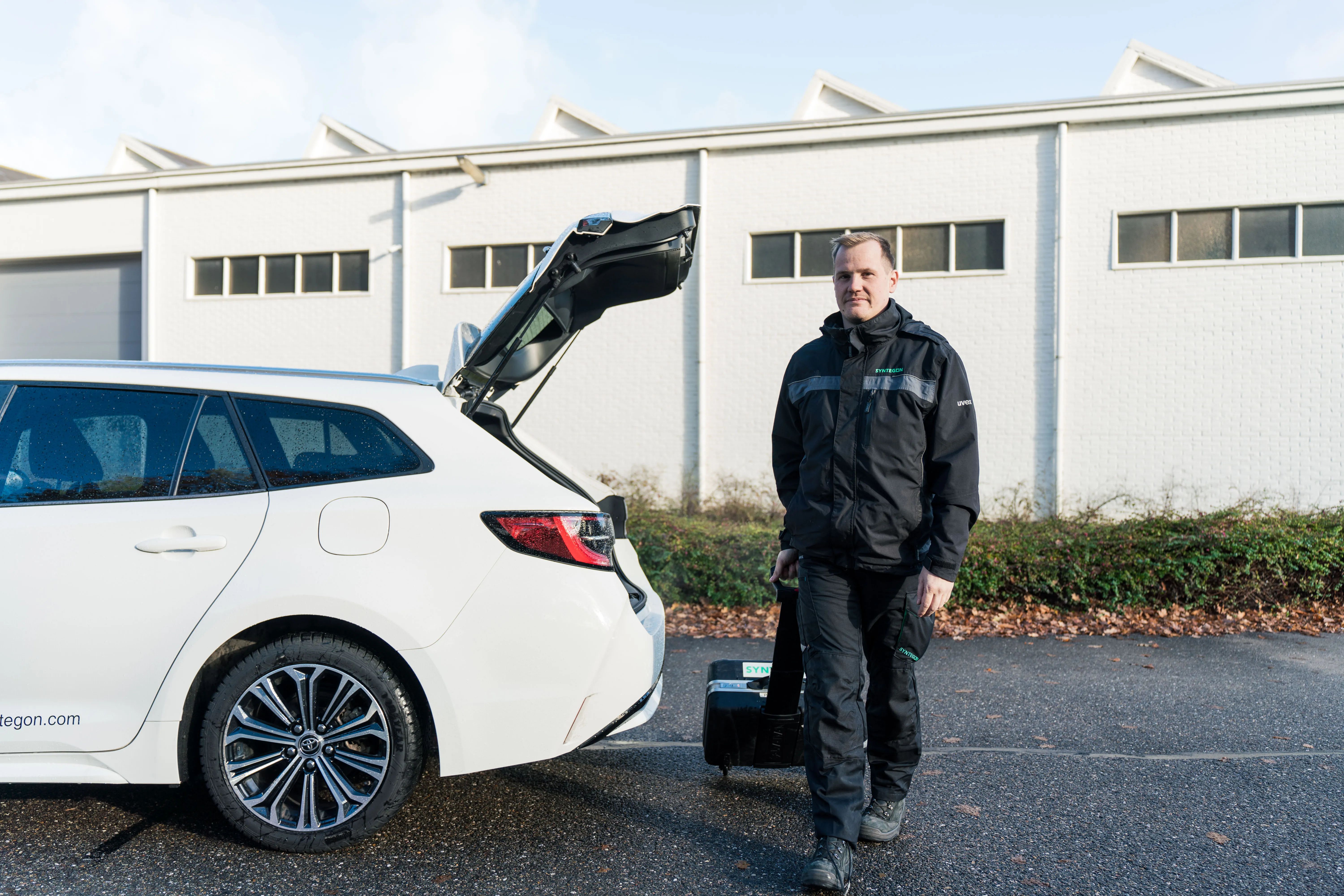 Mann in Arbeitskleidung vor Auto