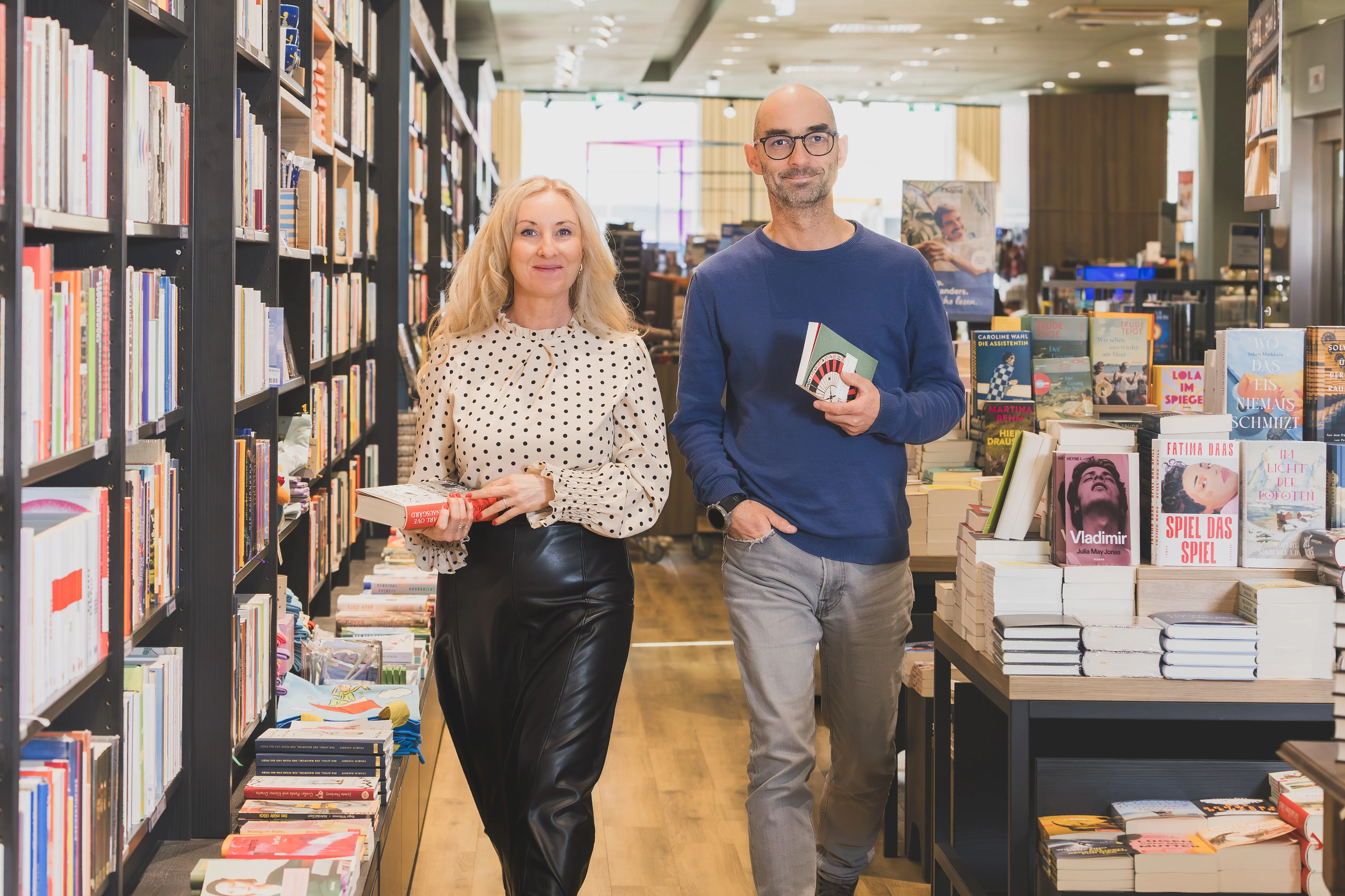 Sechs junge Menschen stöbern gemeinsam in Büchern bei Thalia, umgeben von bunten Buchregalen und gemütlicher Atmosphäre.