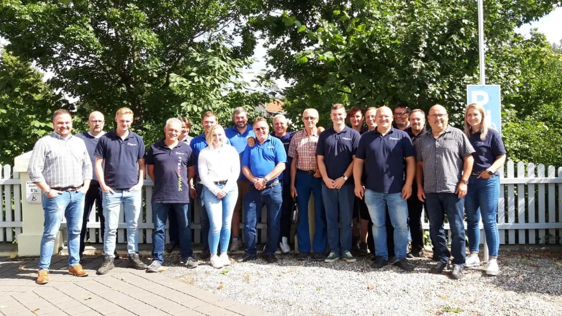 Eine Gruppe von Mitarbeitenden der TIMAC AGRO Deutschland steht draußen lächelnd zusammen für ein Teamfoto.