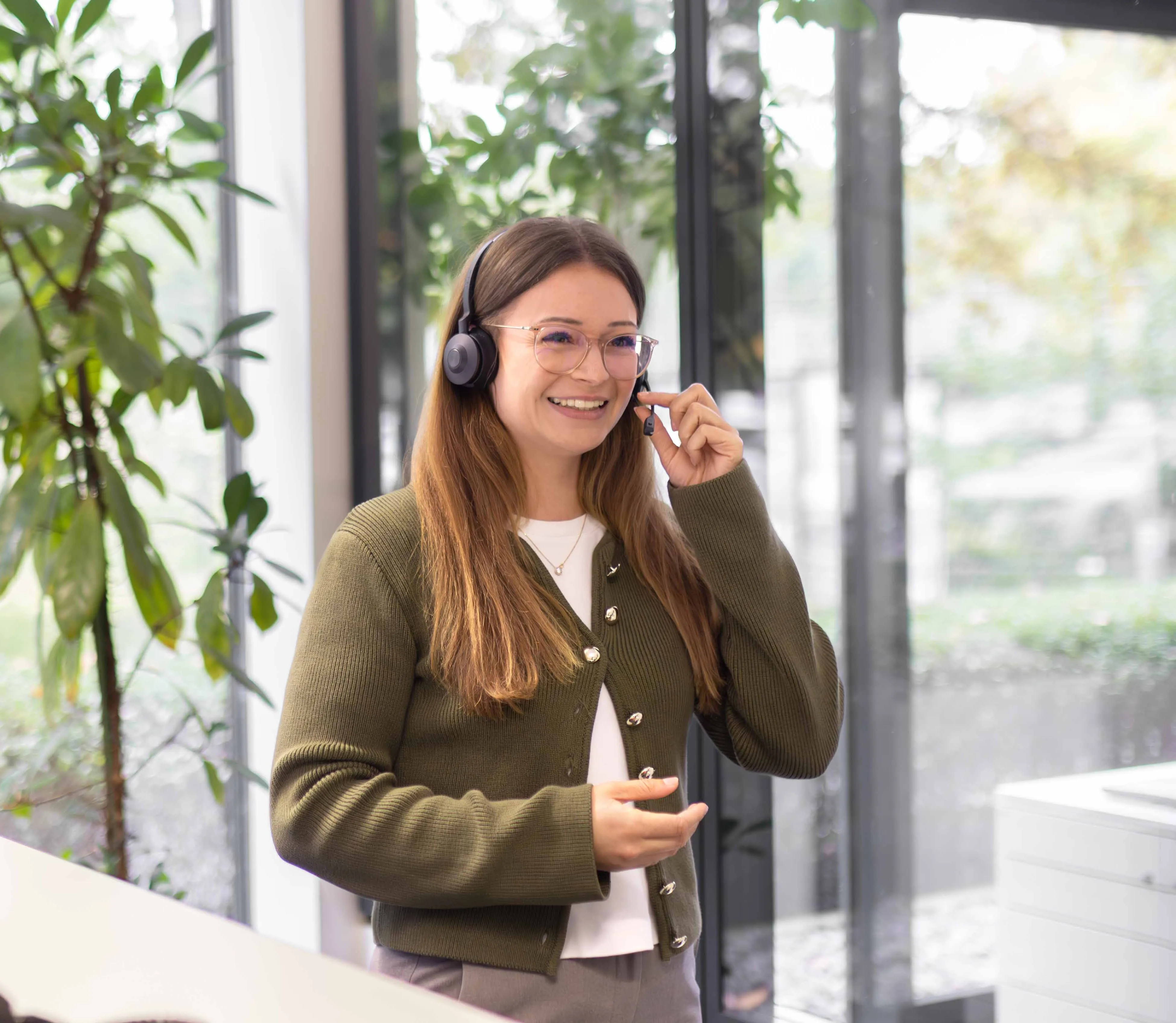 Mitarbeiterin mit Headset beim Telefonieren im Büro.