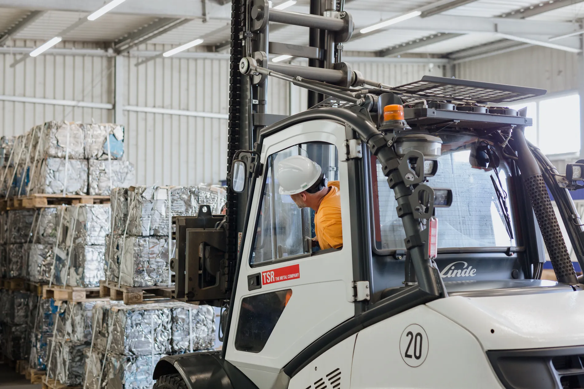 Du bedienst einen Gabelstapler in einer Lagerhalle bei TSR Group und bewegst recyceltes Metall.