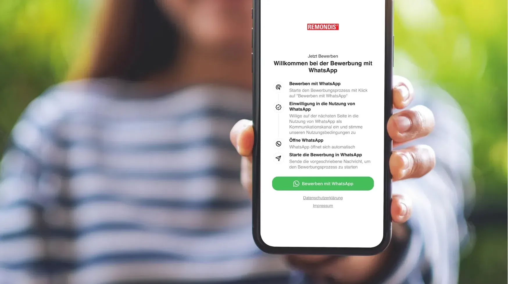 Frau zeigt ein Smartphone mit geöffneter WhatsApp-Bewerbung.