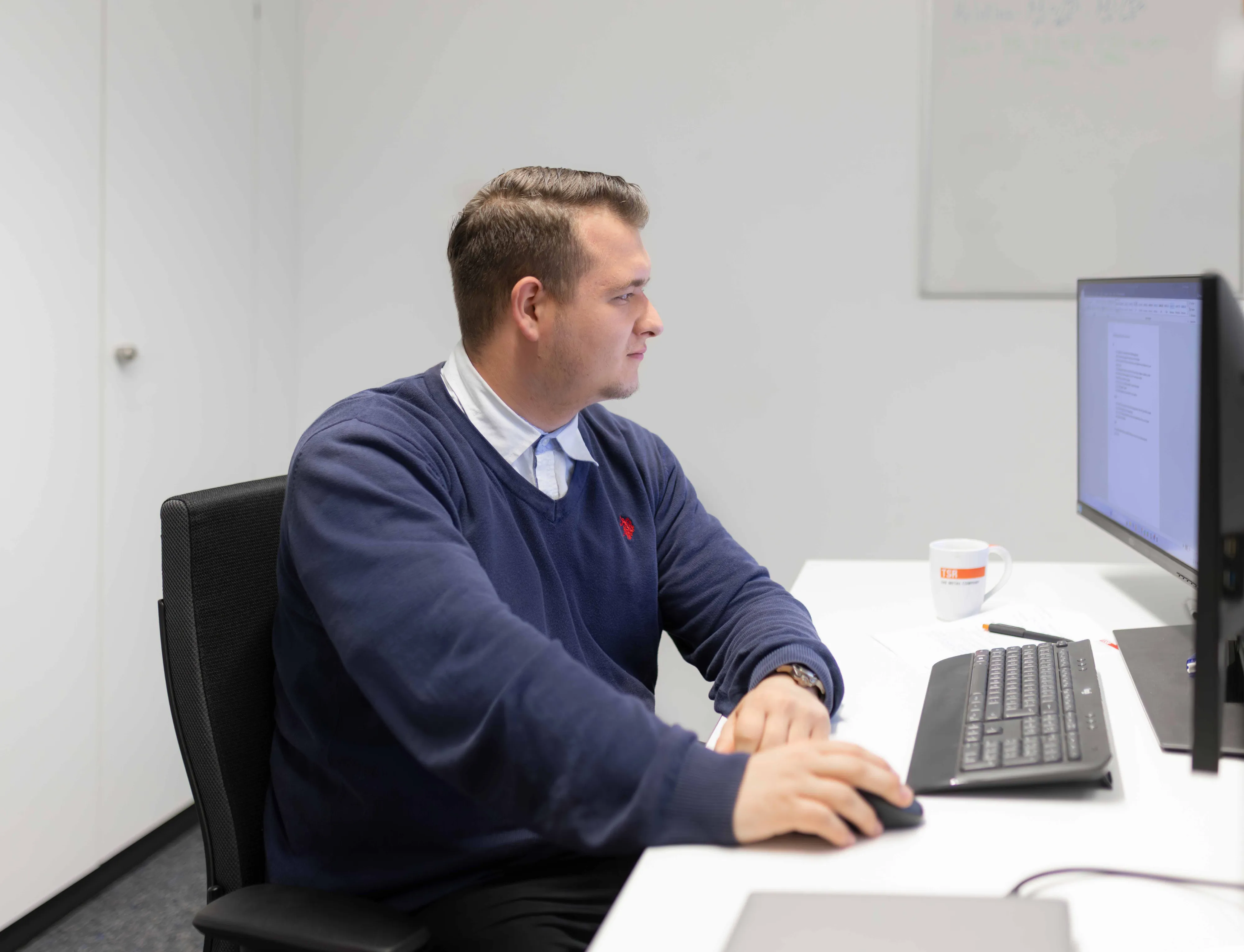 Ein Azubi der TSR Group arbeitet konzentriert am PC in einem modernen Büro.