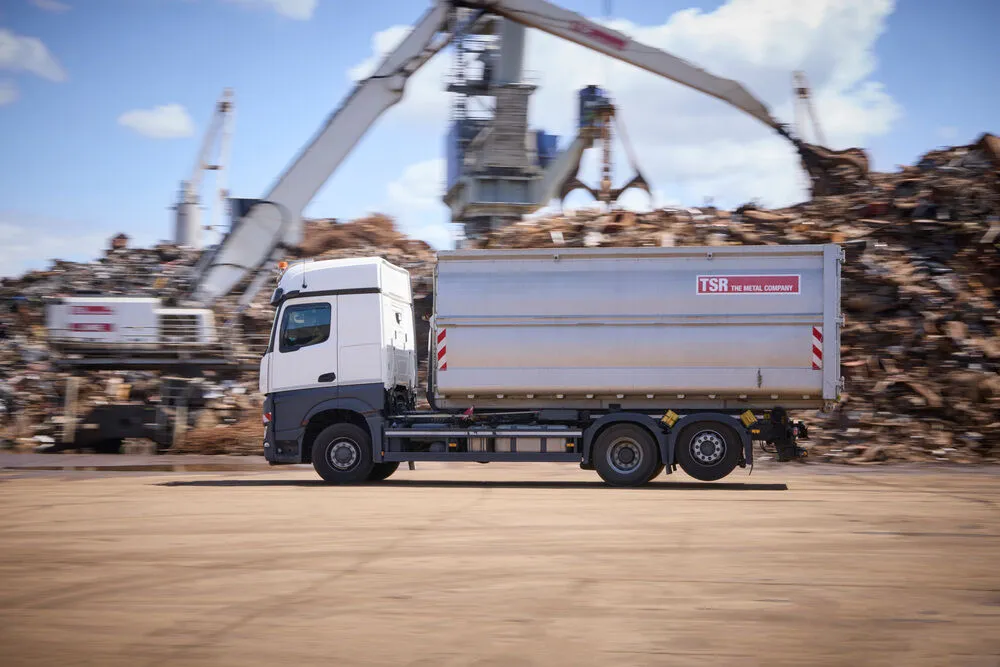 LKW auf dem Betriebsgelände, im Hintergrund Altmetall und Bagger.