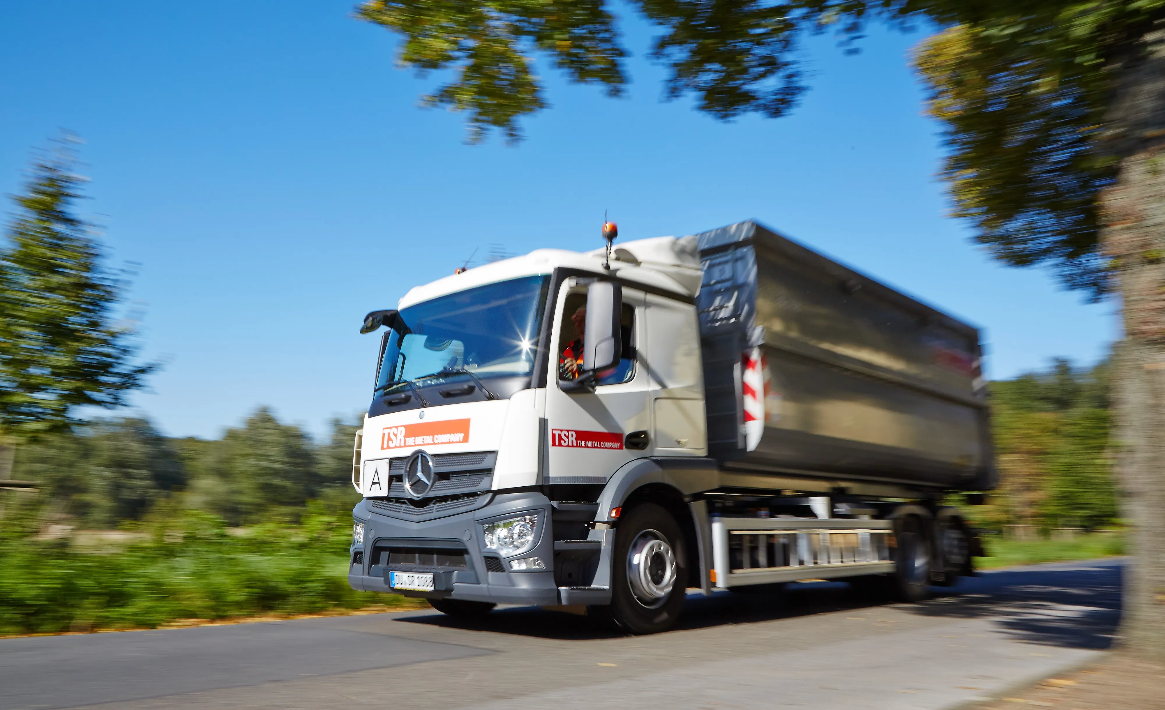 Ein Lkw mit TSR-Logo fährt auf einer Landstraße.