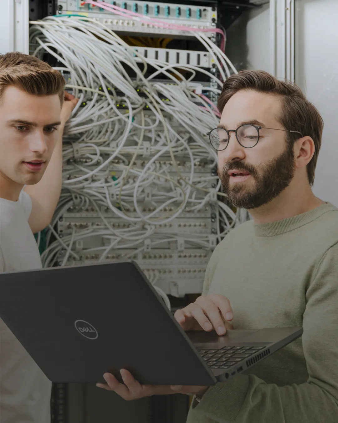 Zwei Kollegen überprüfen gemeinsam Serverkabel und Daten im Rechenzentrum bei TSR Group GmbH & Co. KG.