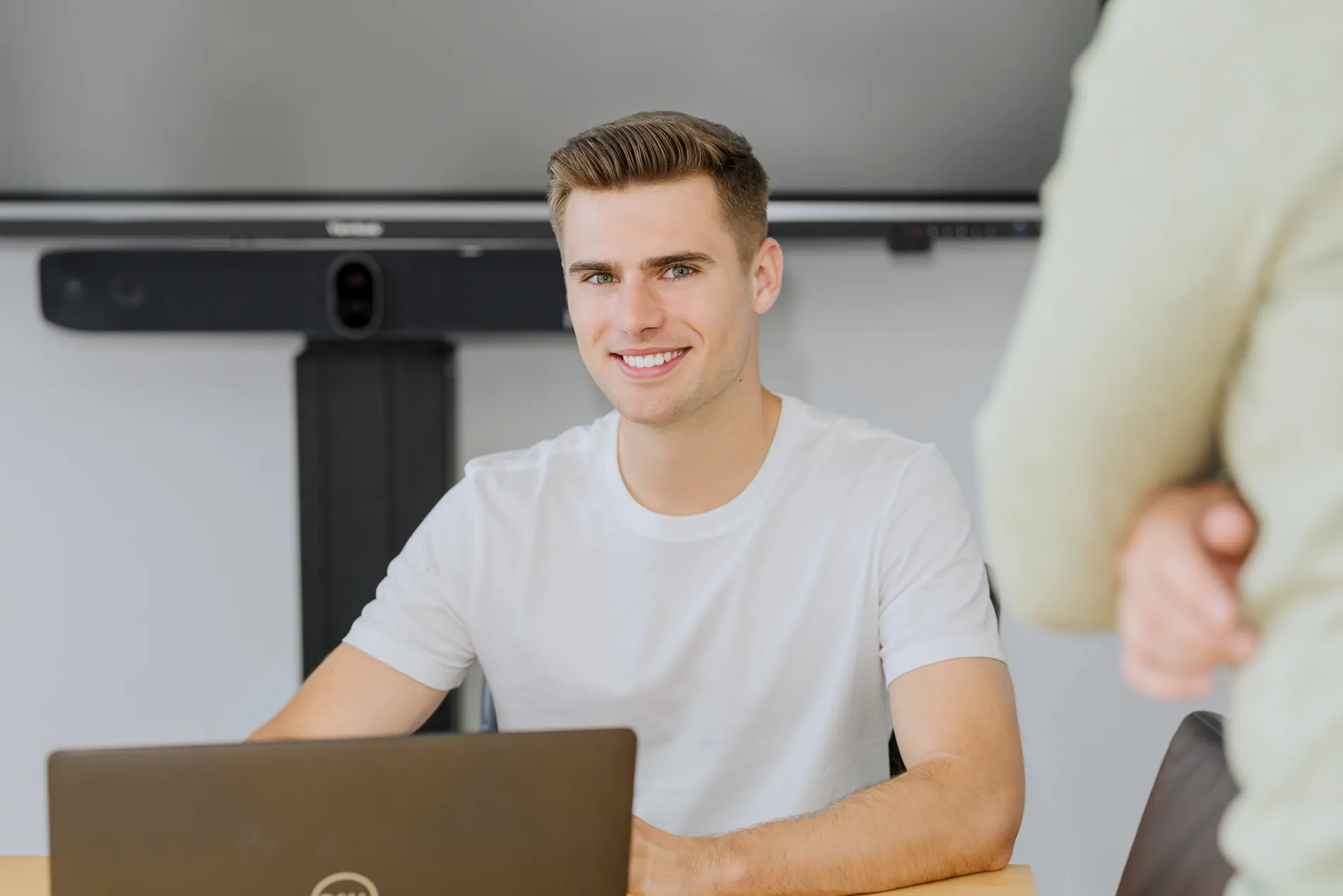 Junger Mann arbeitet am Laptop und lächelt, freundliche Atmosphäre im Büro der Energiebranche bei TSR Group.