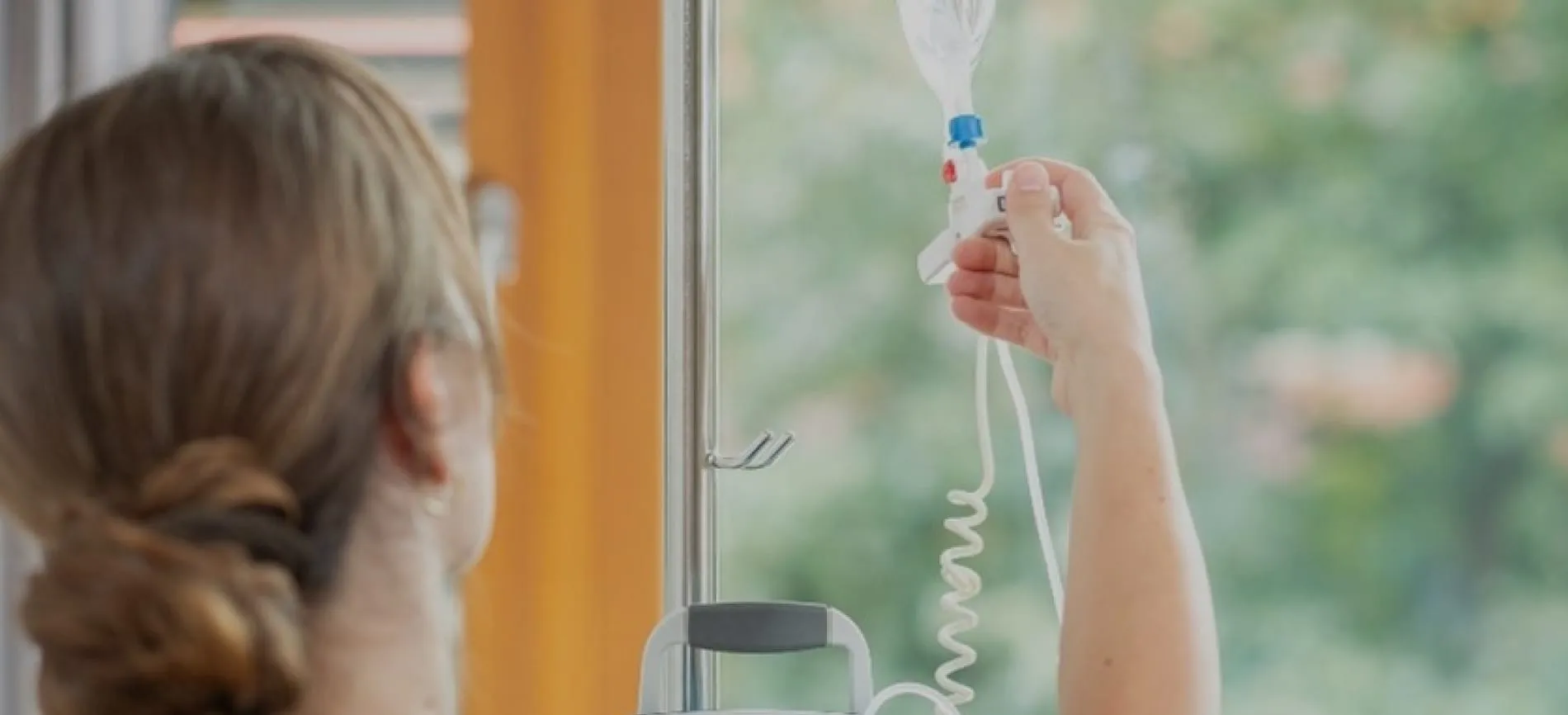 Du siehst eine Pflegekraft, die eine Infusion an einem Ständer im Universitäts-Kinderspital beider Basel vorbereitet.
