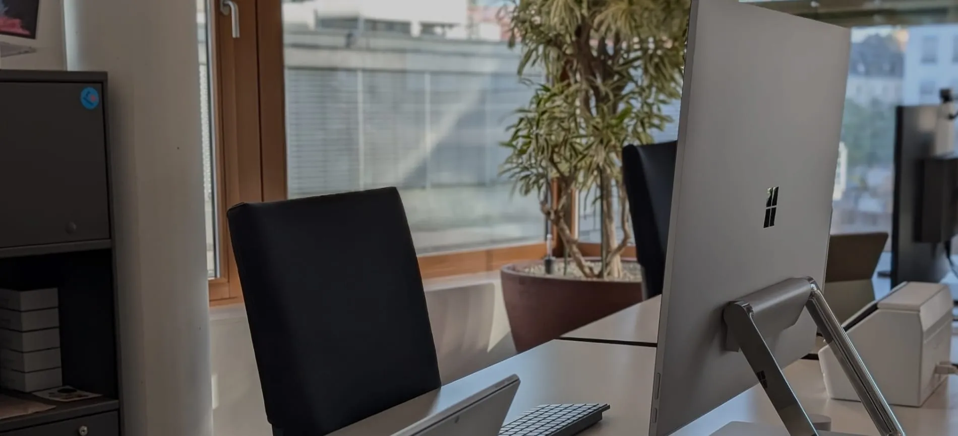 Moderner Arbeitsplatz mit Computer und Blick auf große Fenster, bereit für deinen Einstieg beim UKBB im Gesundheitsbereich.
