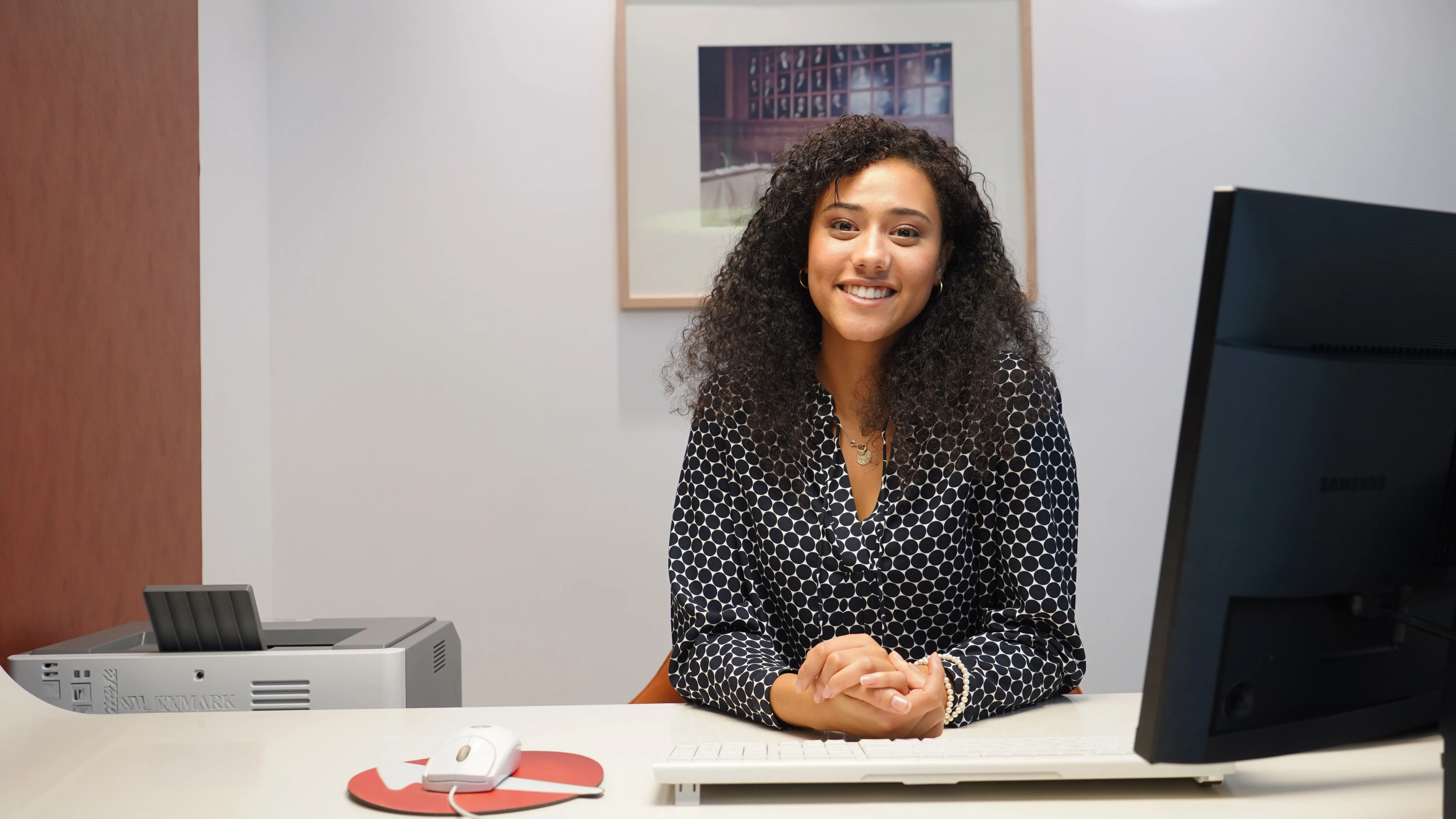 Smiling woman sitting at a desk in front of a computer.  