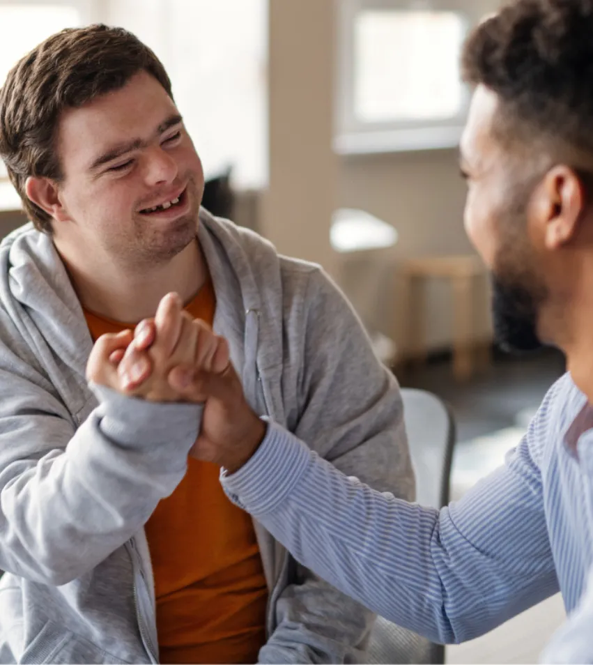 Zwei Männer lächeln sich an und geben sich motivierend die Hand
