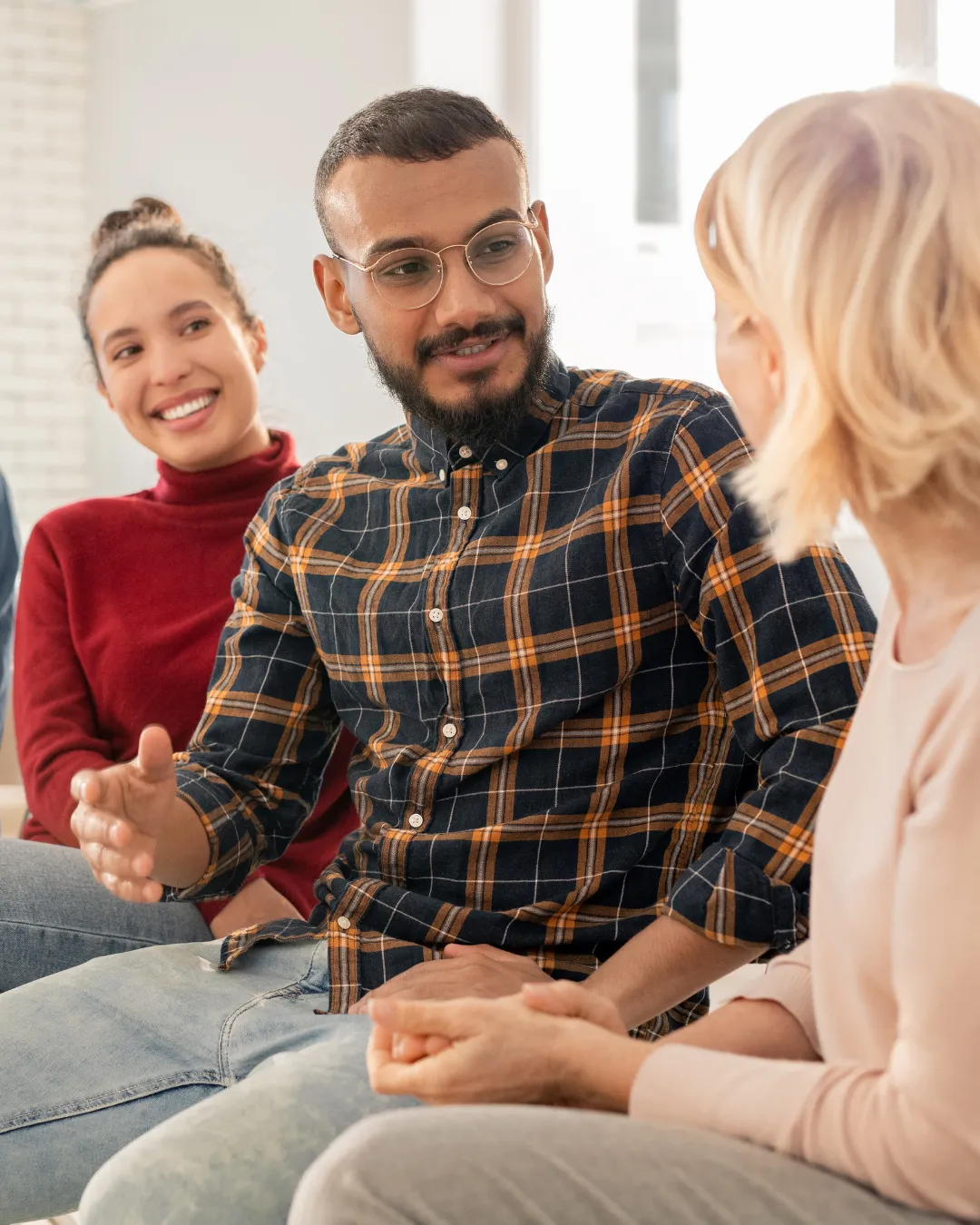 Eine Betreuerin liest lachend einem Kind ein Buch vor, umgeben von anderen Kindern in einem gemütlichen Raum.