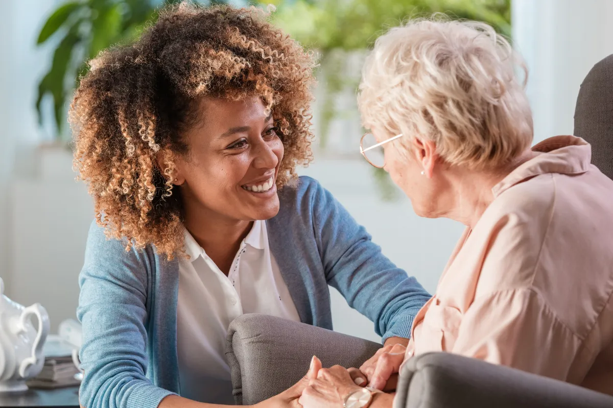 Junge Pflegerin in einem freundlichen Gespräch mit einer älteren Dame. Ideal für eine Karriere im Gesundheitssektor bei Unionhilfswerk.