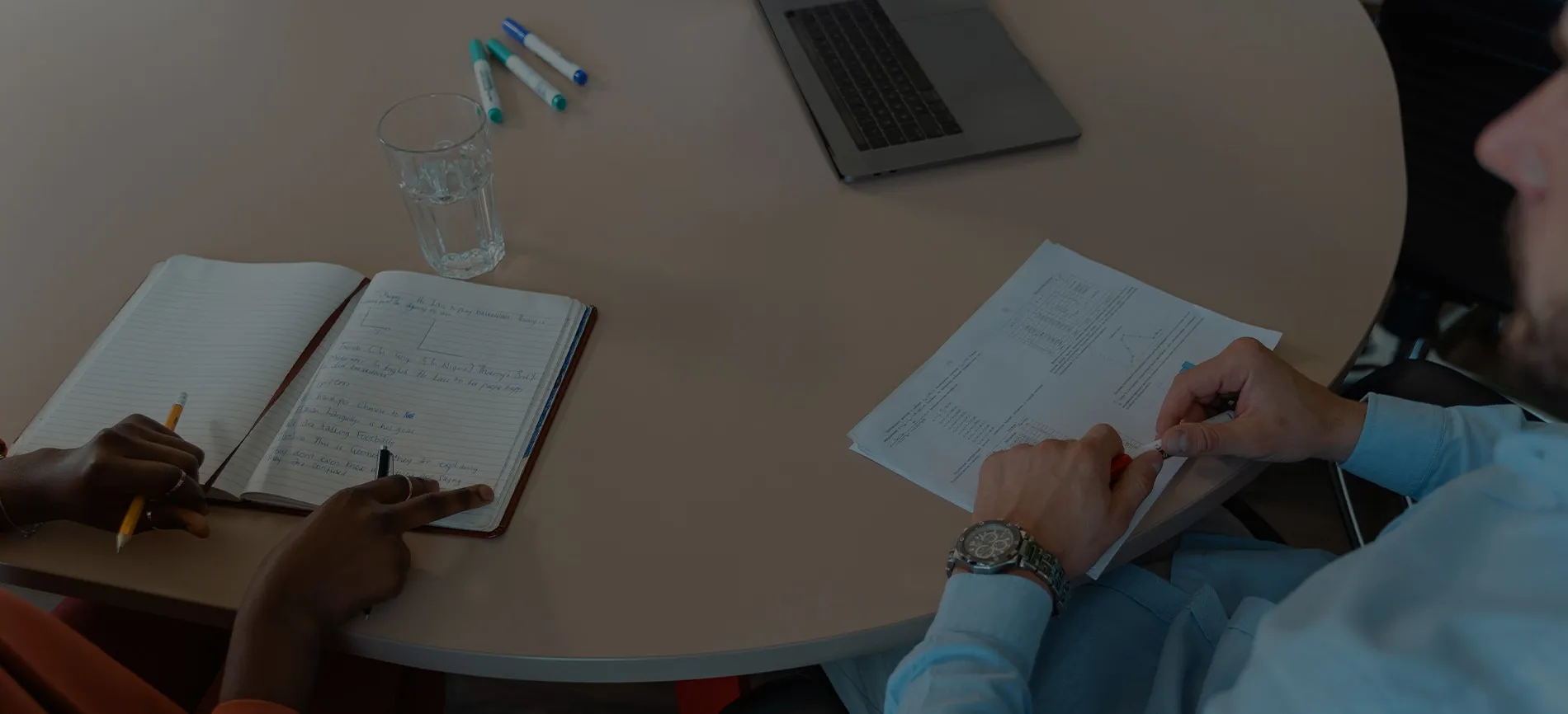 Zwei Personen arbeiten gemeinsam an einem Tisch mit Laptop, Notizbuch und Unterlagen – Deine Chance bei VAG.