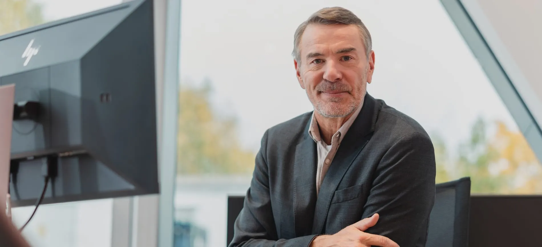 Ein lächelnder Geschäftsmann im Anzug sitzt in einem modernen Büro von Volkswagen Retail GmbH.