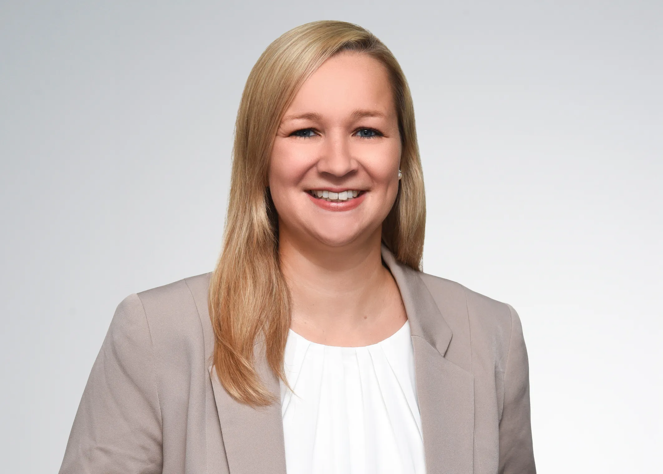 Freundliche Bankmitarbeiterin im Business-Outfit lächelt, um dich auf der Karriereseite der VR Bank willkommen zu heißen.