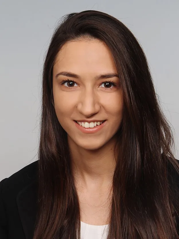 Junge Frau mit langen braunen Haaren lächelt freundlich im Business-Outfit, geeignet für die Karriere bei VR Bank.