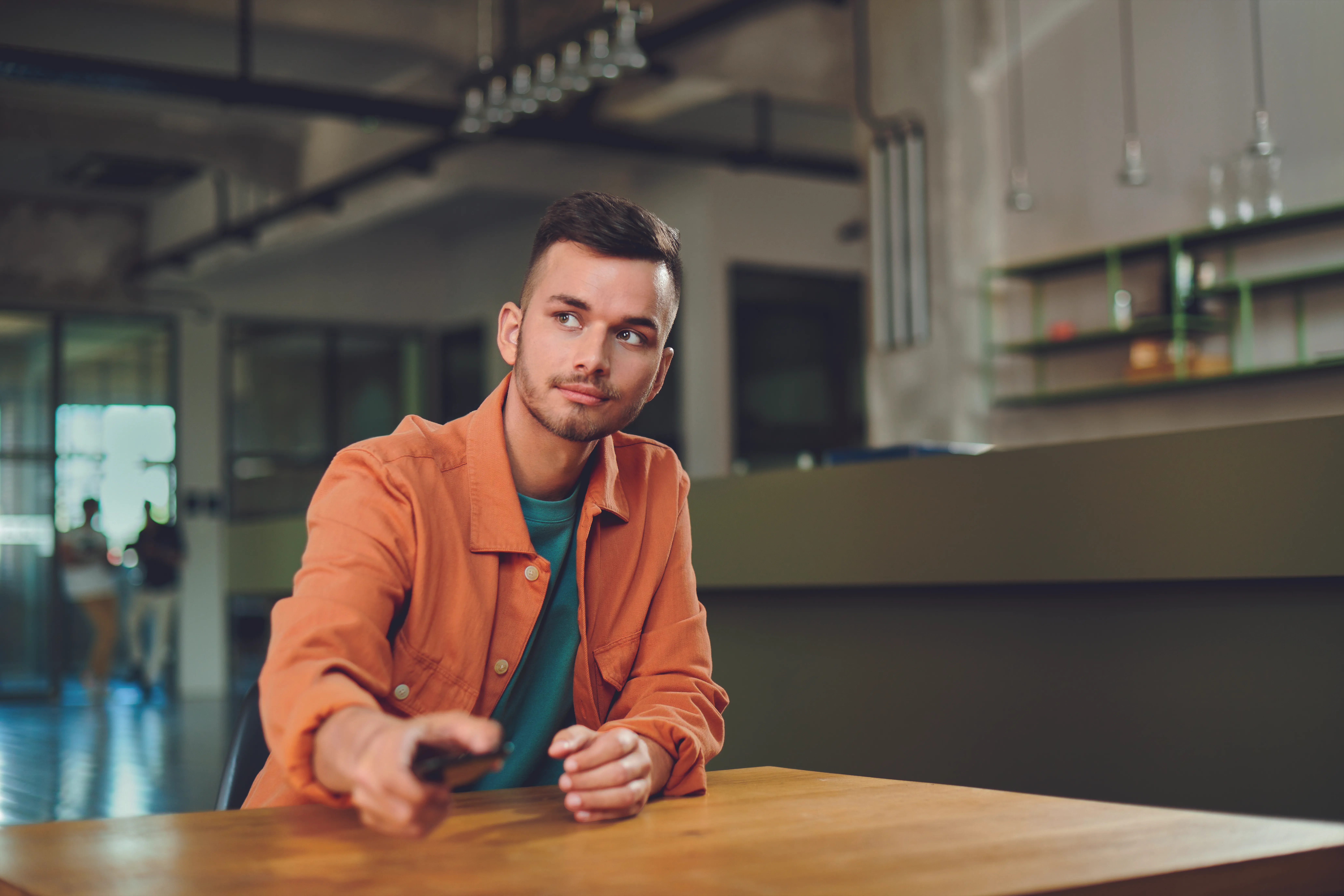 Junger Mann im modernen Büro, der interessiert in die Runde blickt – starte Deine Karriere bei der VR Bank.