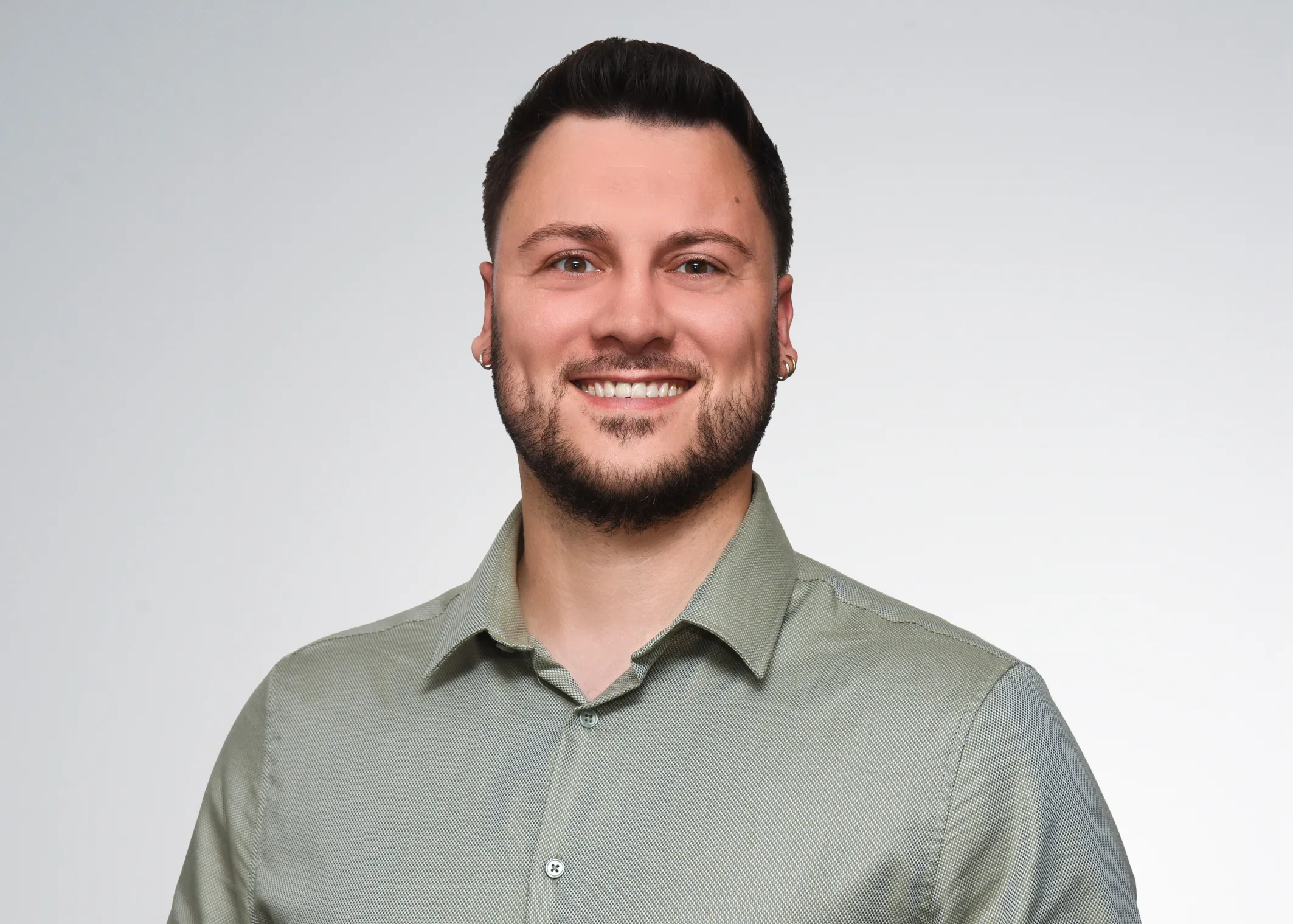 Junger Mann im Hemd lächelt freundlich in die Kamera, ideal für den Karrierebereich bei der VR Bank.