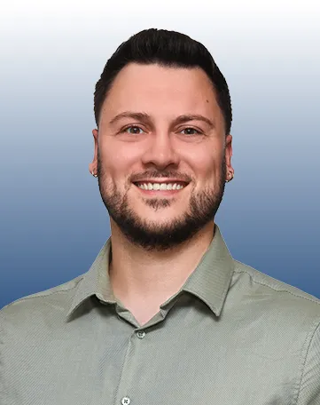 Junger Mann im Hemd lächelt freundlich in die Kamera, ideal für den Karrierebereich bei der VR Bank.