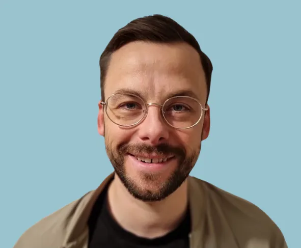 Lächelnder Mann mit Brille vor blauem Hintergrund