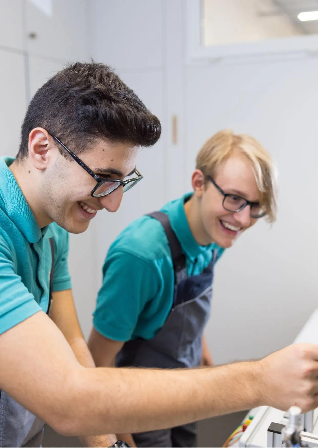Zwei Auszubildende arbeiten gemeinsam mit Freude an einer technischen Anlage im Bereich Energie und Versorgung.