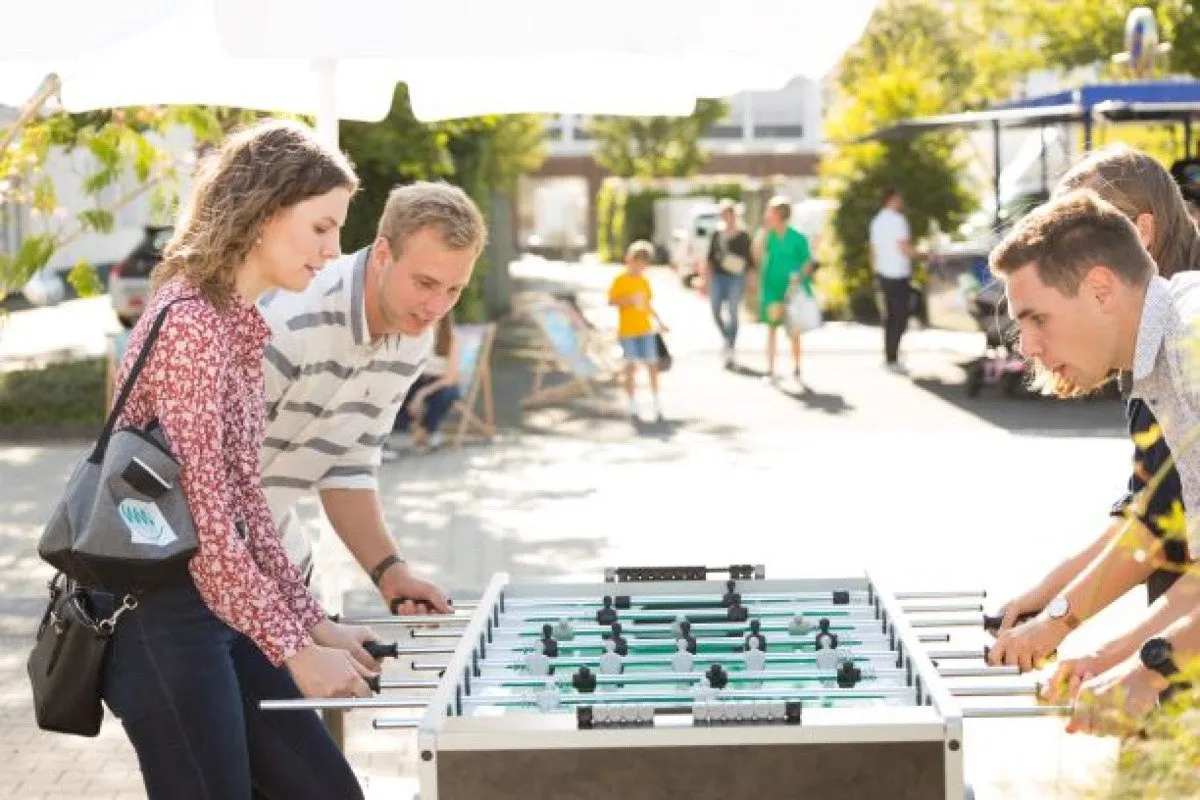 Menschen spielen Tischfußball im Freien.