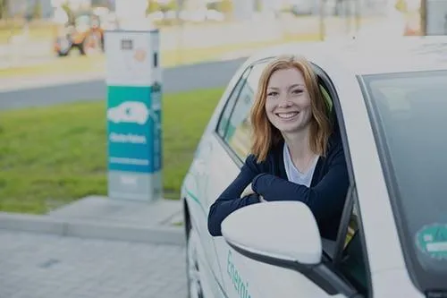 Frau im Auto lächelt in die Kamera.