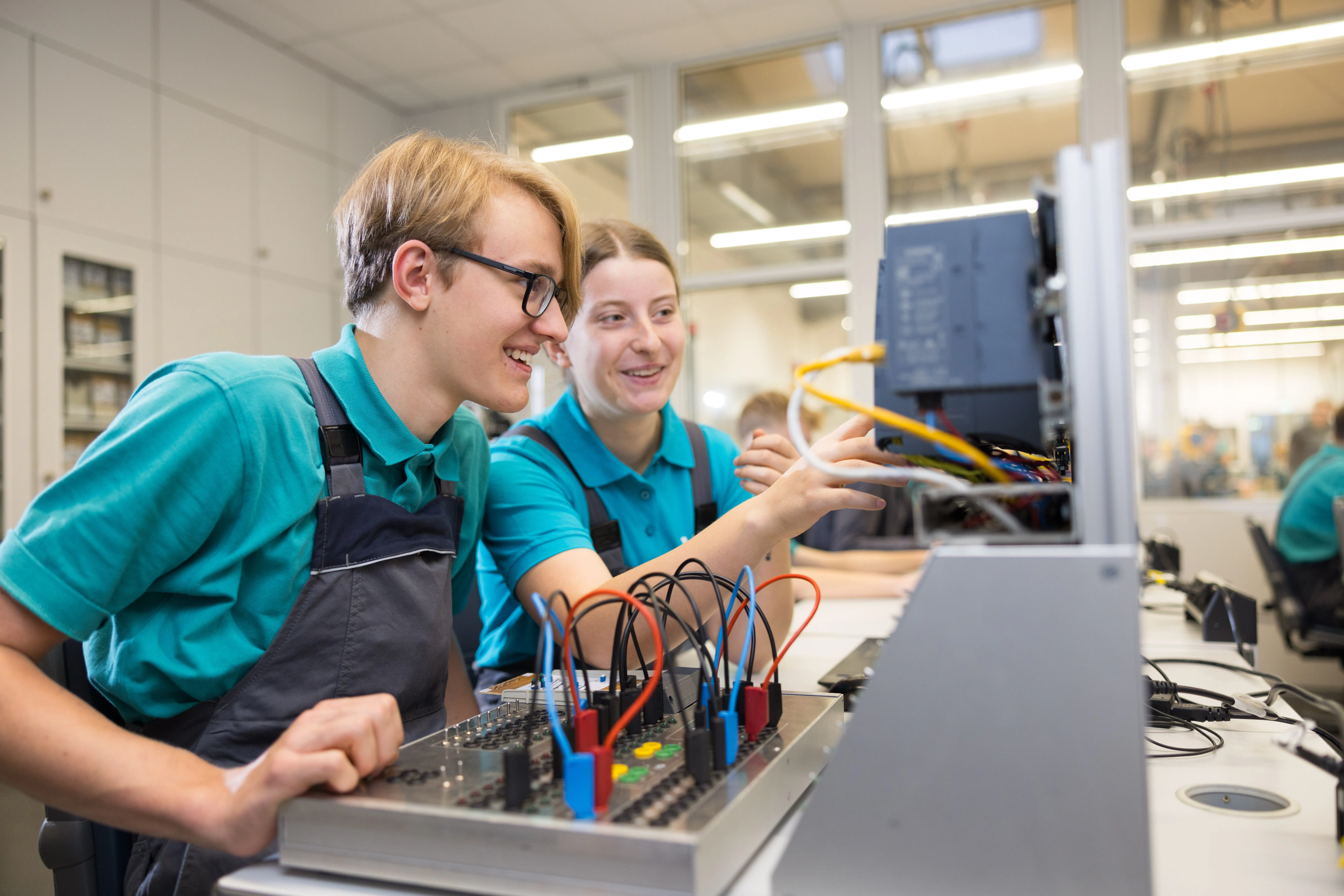 Zwei Auszubildende arbeiten gemeinsam an einem technischen Versuchsaufbau im Bereich Energieversorgung.