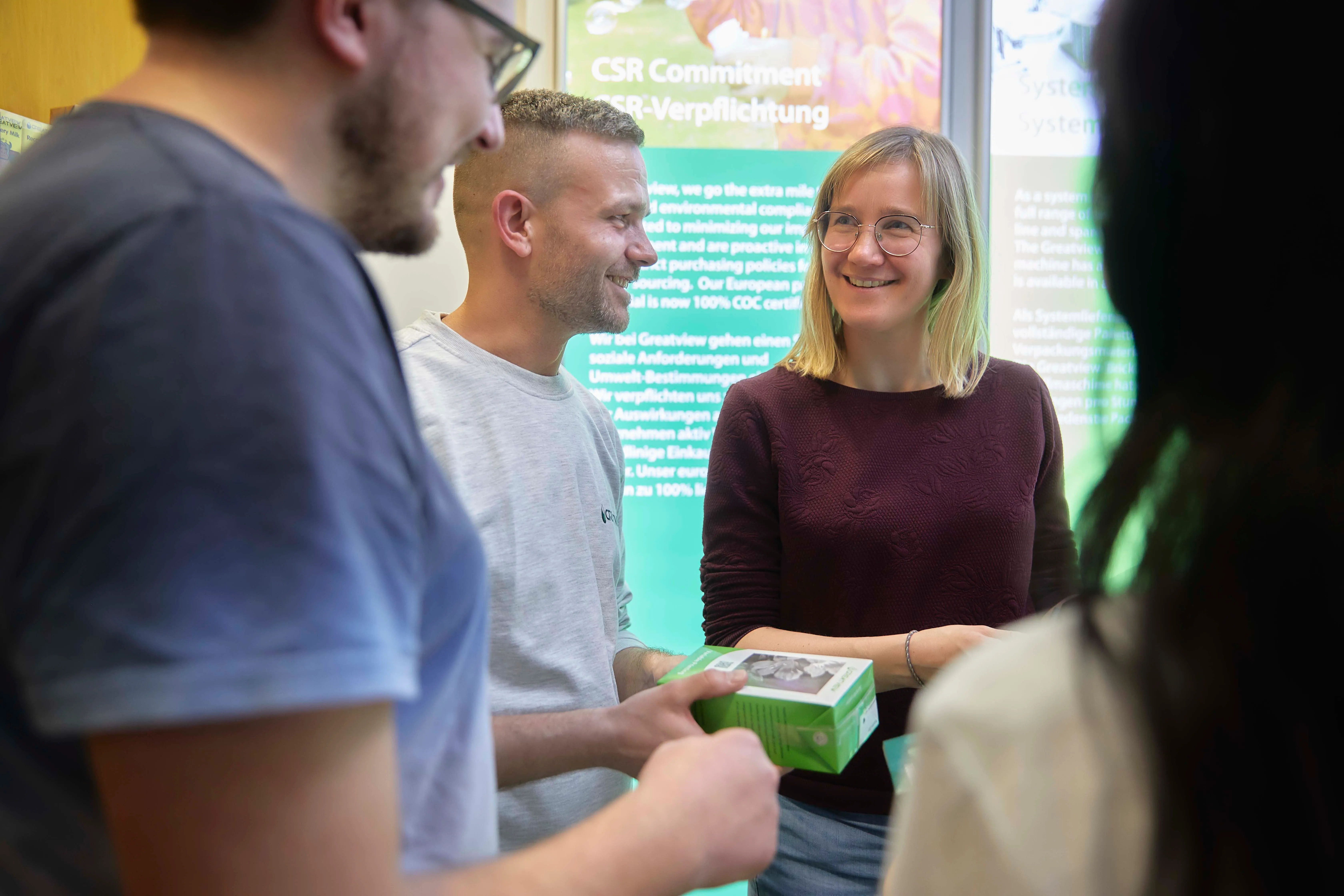 Eine Gruppe von vier jungen Fachleuten unterhält sich fröhlich in einem Büro bei Wintipak.