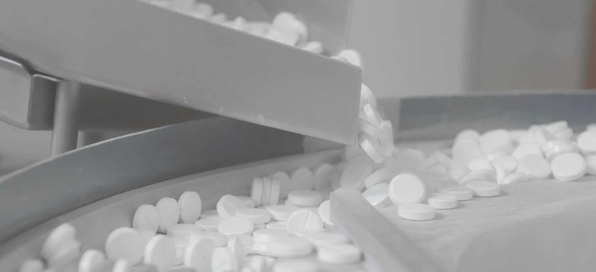 Ein Arzt im Gespräch mit einer Person, zeigt Tablettenblister am Schreibtisch bei Wörwag Pharma.