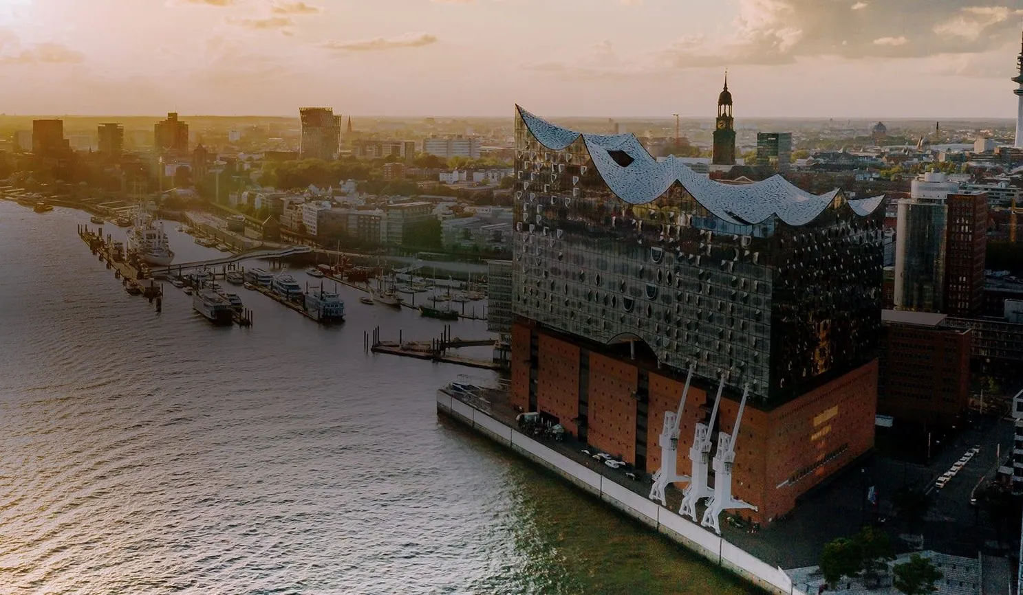 Sunset view of Hamburg's harbor featuring the Elbphilharmonie, blending modern architecture with a vibrant city vibe.