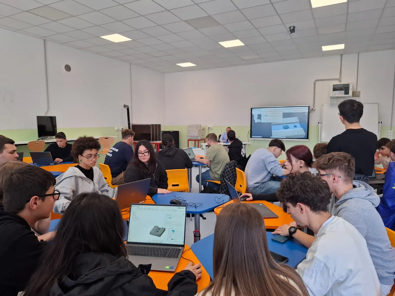 Junge Menschen arbeiten gemeinsam an Laptops an technischen Projekten in einem modernen Klassenraum bei ZF Friedrichshafen AG.