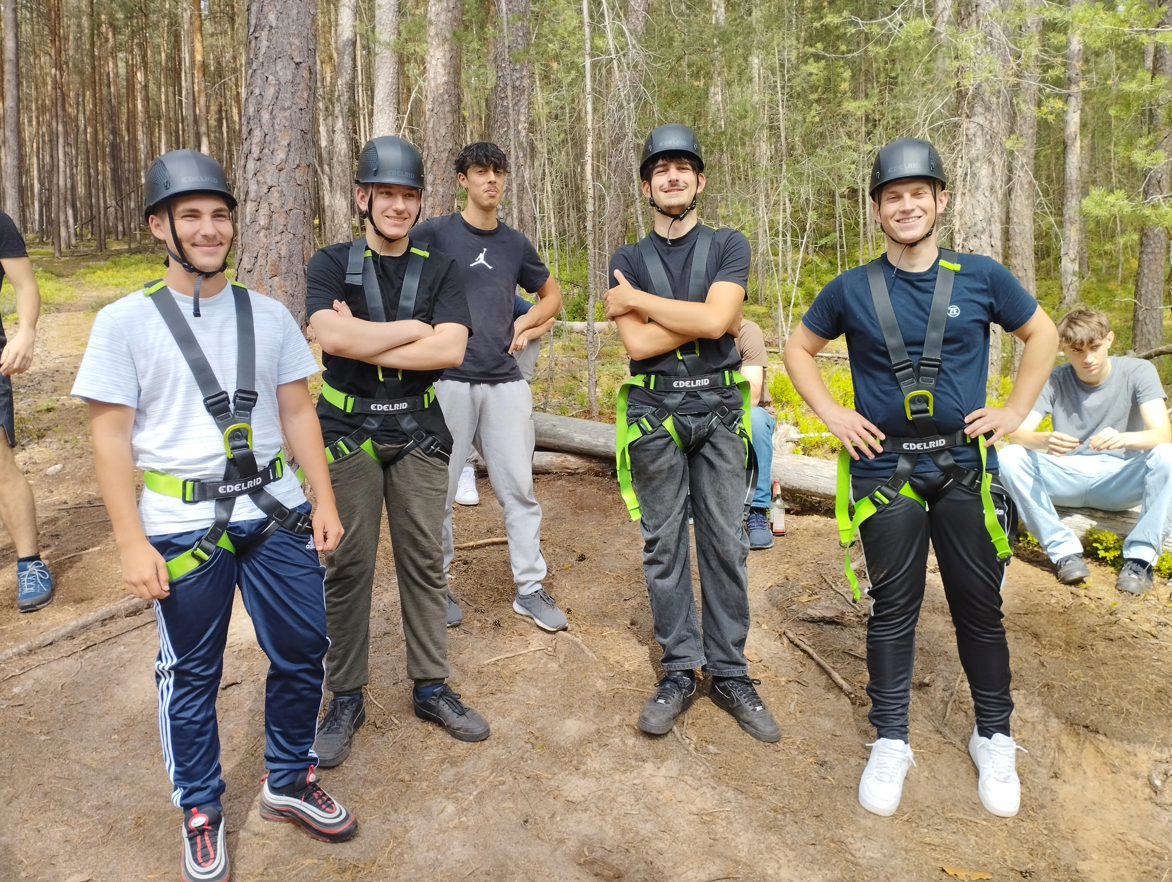 Junge Teammitglieder mit Kletterausrüstung und Helmen im Wald – gemeinsam Abenteuer erleben bei ZF Friedrichshafen AG.