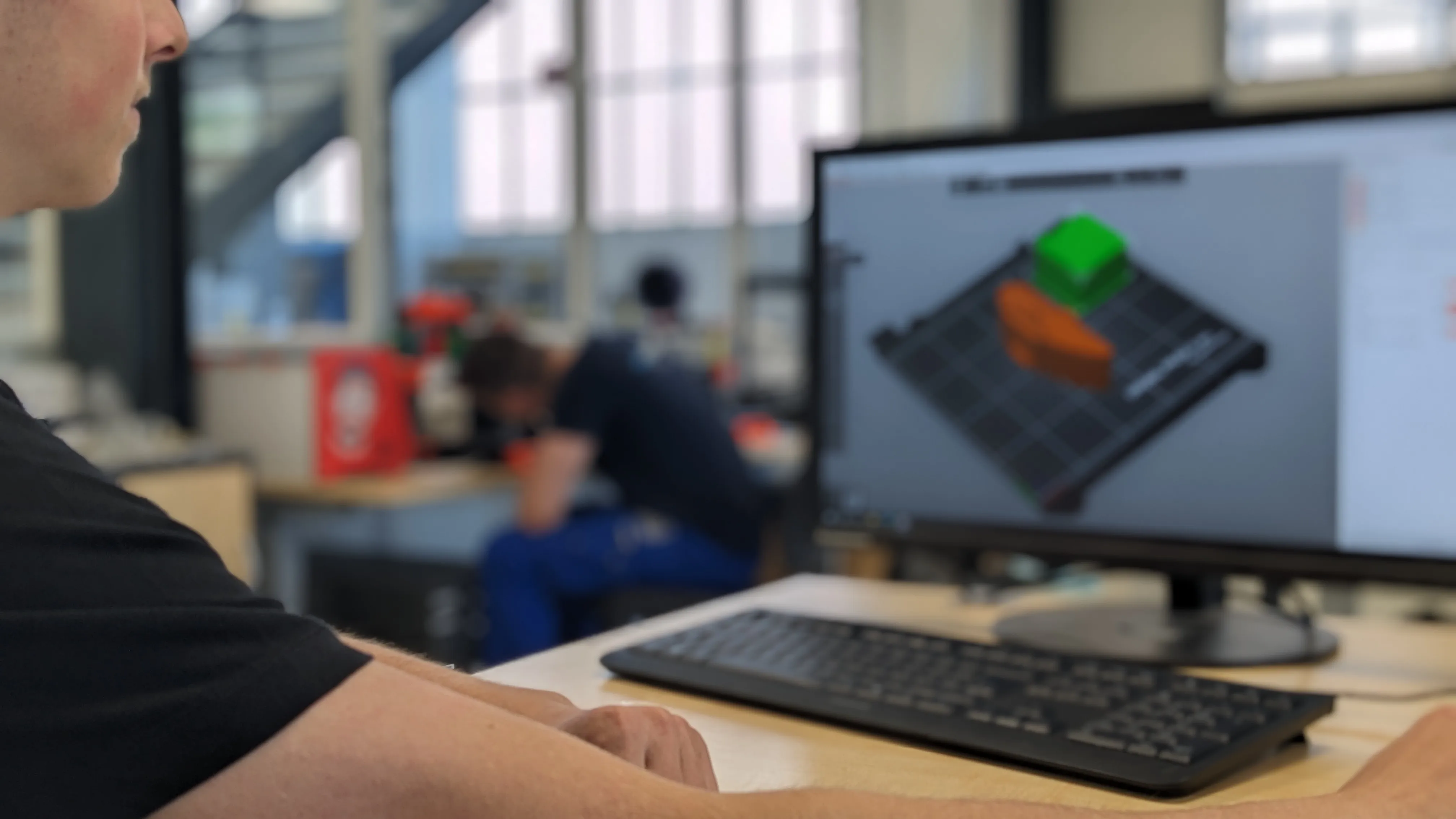 Du siehst einen Arbeitsplatz bei ZF, an dem am Computer ein 3D-Modell für die Automobilindustrie entwickelt wird.